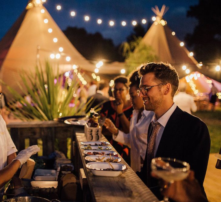 Festoon Lights | Bride in La Sposa Gown from Mirror Mirror Bridal | Groom in Paul Smith Suit | Outdoor Wedding Ceremony &amp; Tipi Reception Planned by Benessamy Events | Red on Blonde Photography