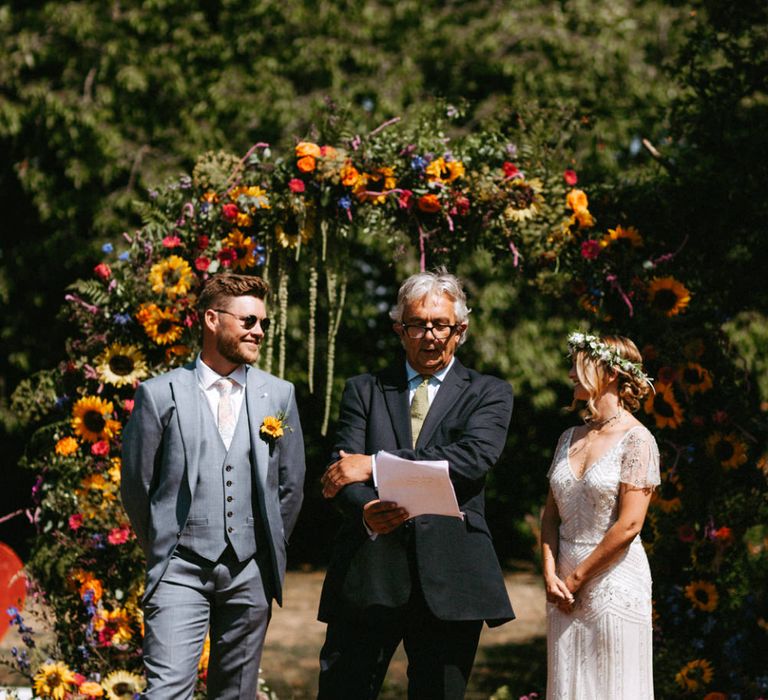 Outdoor Wedding Ceremony with Floral Moon Gate, Bride in Jenny Packham Portia Wedding Dress and Groom in Grey Ted Baker Suit