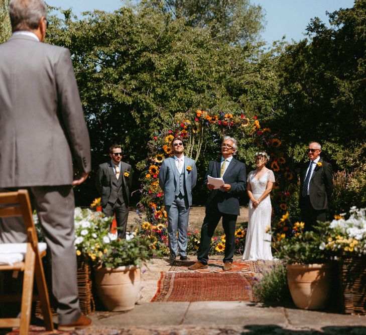 Outdoor Wedding Ceremony with Floral Moon Gate, Bride in Jenny Packham Portia Wedding Dress and Groom in Grey Ted Baker Suit