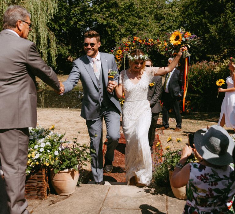 Bride in Jenny Packham Portia Wedding Dress and Groom in Grey Ted Baker Suit Walking up the Aisle as husband &amp; Wife