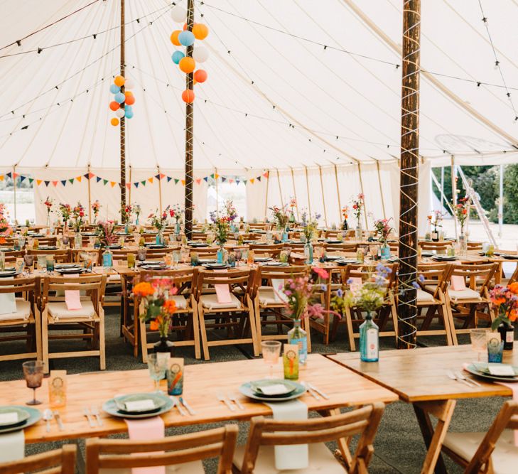 Colourful Marquee Wedding Reception Decor with Wooden Tables and Wild Flowers