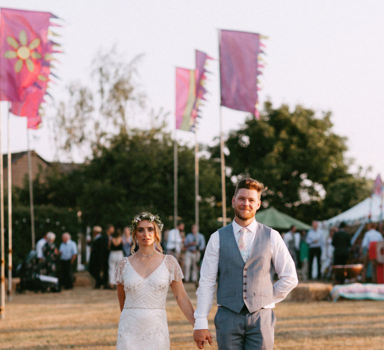 Boho Bride in Jenny Packham Portia Wedding Dress and Flower Crown and Groom in Grey Ted Baker Suit  Holding Hands