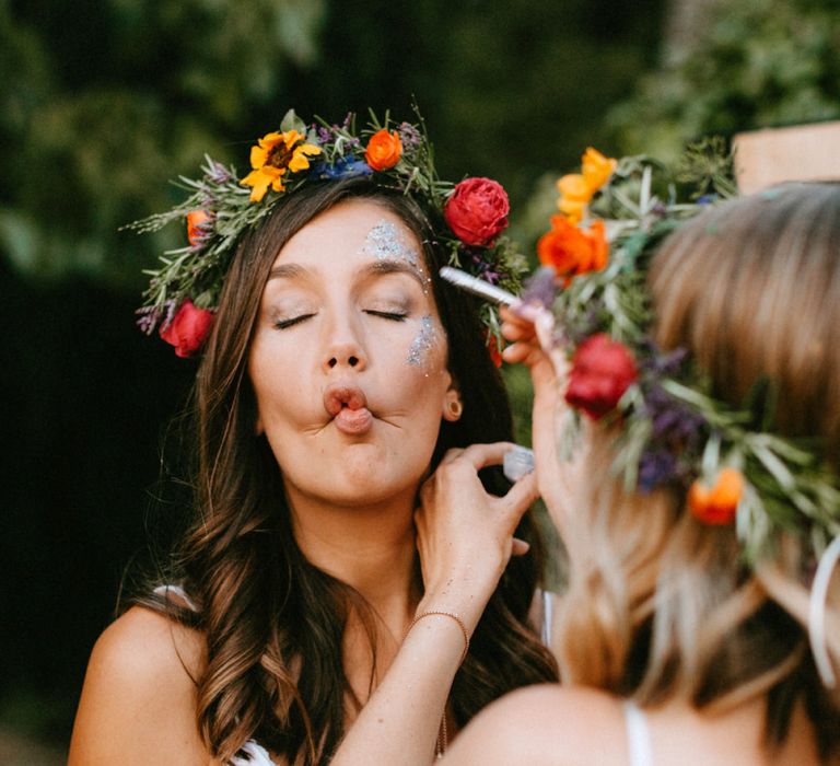 Bridesmaid in White Dress and Colourful Flower Crown putting on Face Glitter