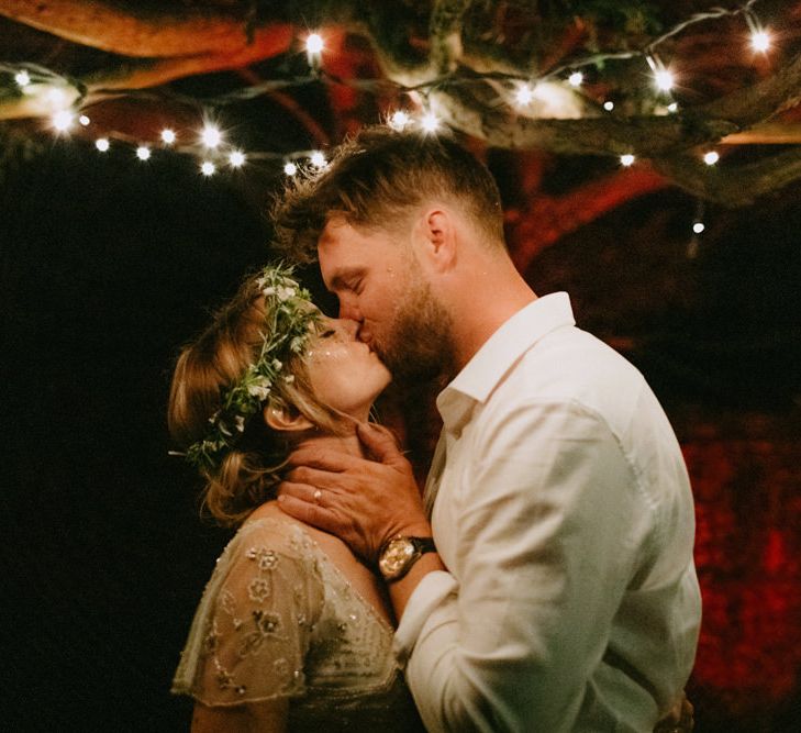 Bride in Jenny Packham Portia Wedding Dress and Flower Crown and Groom in Grey Ted Baker Suit Kissing