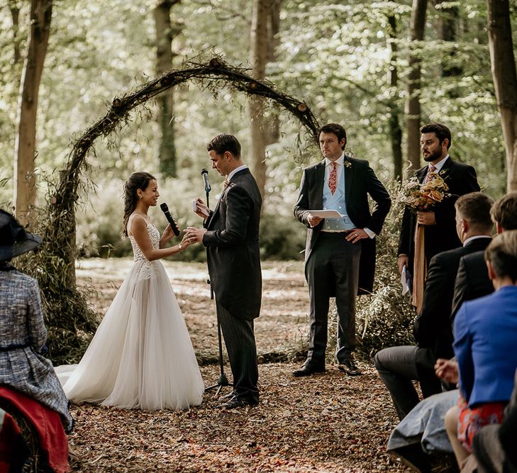 Bride and groom exchanging vows in front of a moon gate at Evenley Wood Garden wedding ceremony