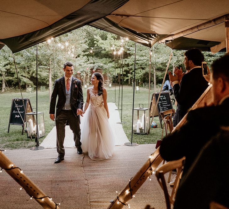 Bride and groom entering the tipi wedding reception