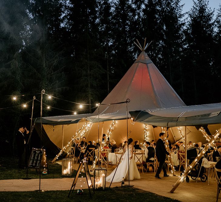 Tipi wedding reception at Evenley Wood Garden with fealty lights wrapped around the poles