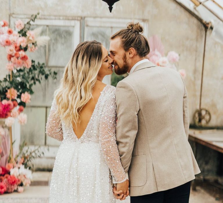 Bride in sequin wedding dress and groom in beige blazer holding hands