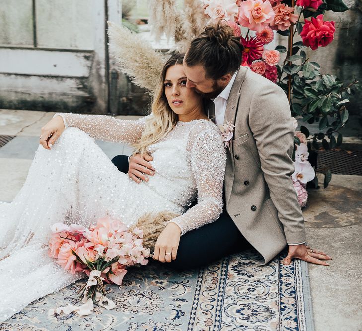 Bride and groom embracing on the floor on an ornate rug