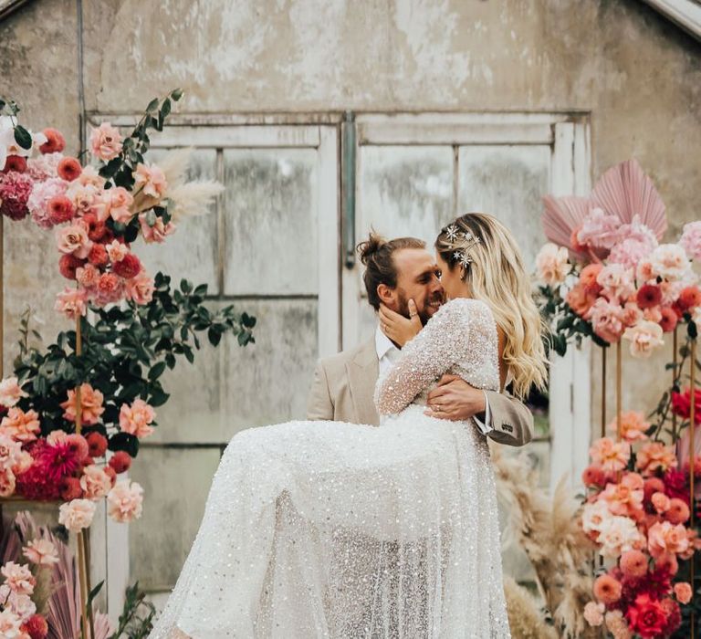 Groom picking his bride up in a sequin wedding dress