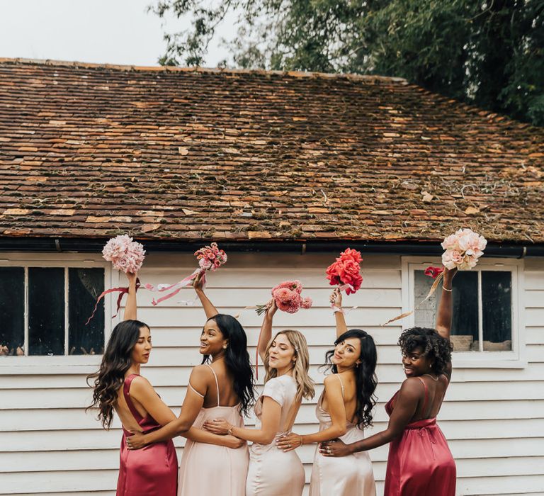 Bridesmaids in different pink dresses holding up their bouquets