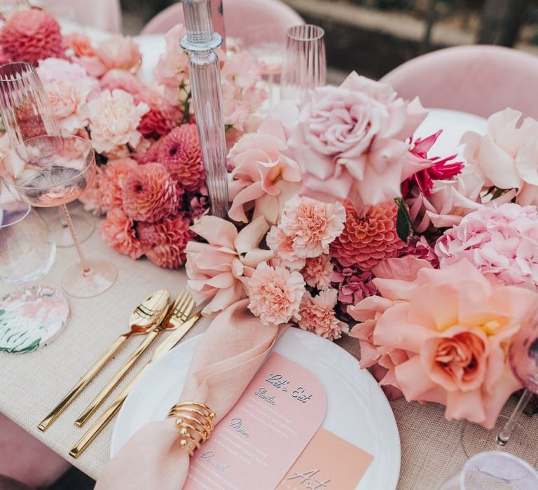 Intimate table scape setting with floral centrepiece, gold cutlery and matching stationery