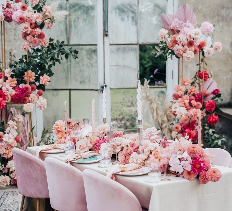 Pink colour scheme tablescape styling with velvet chairs, floral table runner and linens