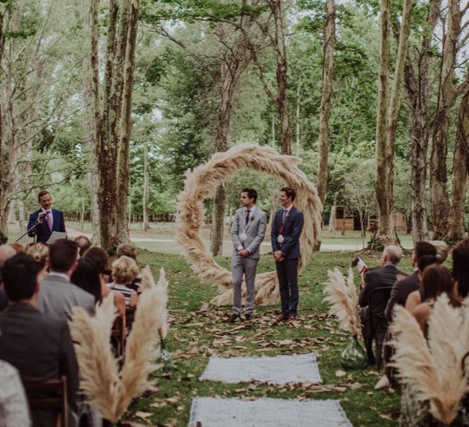 Outdoor Wedding Ceremony | Two Grooms in Grey Suits | Pampas Grass Moon Gate | Woodland Wedding at Sa Farinera de Sant LLuis Wedding Venue, Catalan Empordà, Spain | Planned &amp; Styled by Mille Papillons | HUMà06 Photography | HUMà06 Photography