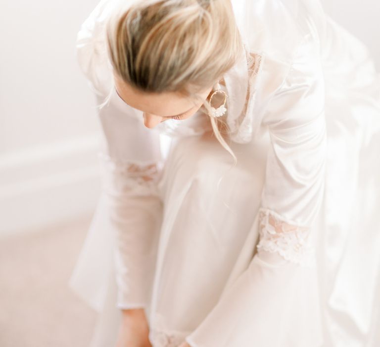 Bride putting on wedding shoes at Prestwold Hall wedding