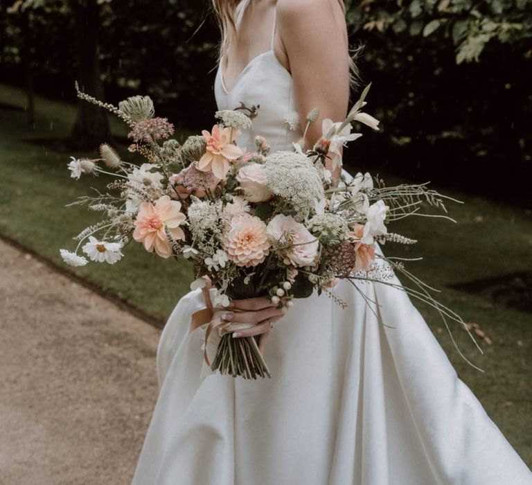 Bride in Emma Beaumont Wedding Dress and Headdress Holding a Peach and White Wedding Bouquet