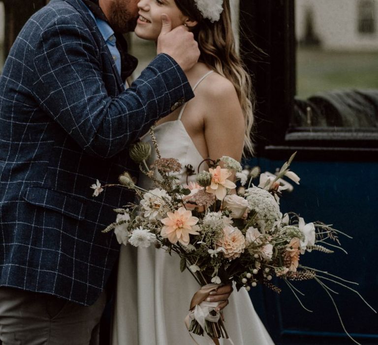 Groom in Blue Check Jacket Kissing His Bride with  White Headdress