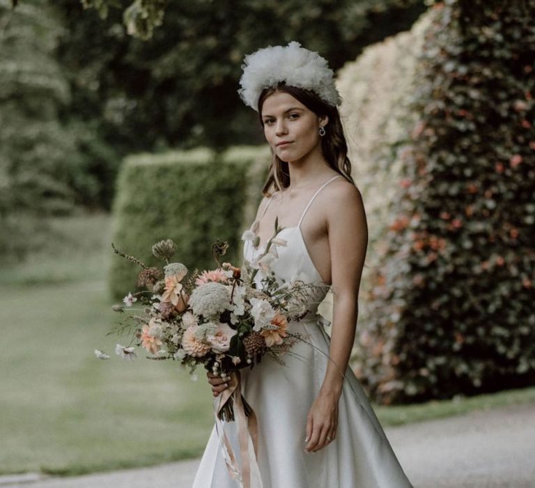 Stylish Bride in Emma Beaumont Wedding Dress with Thin Straps Holding a Peach and White Wedding Bouquet