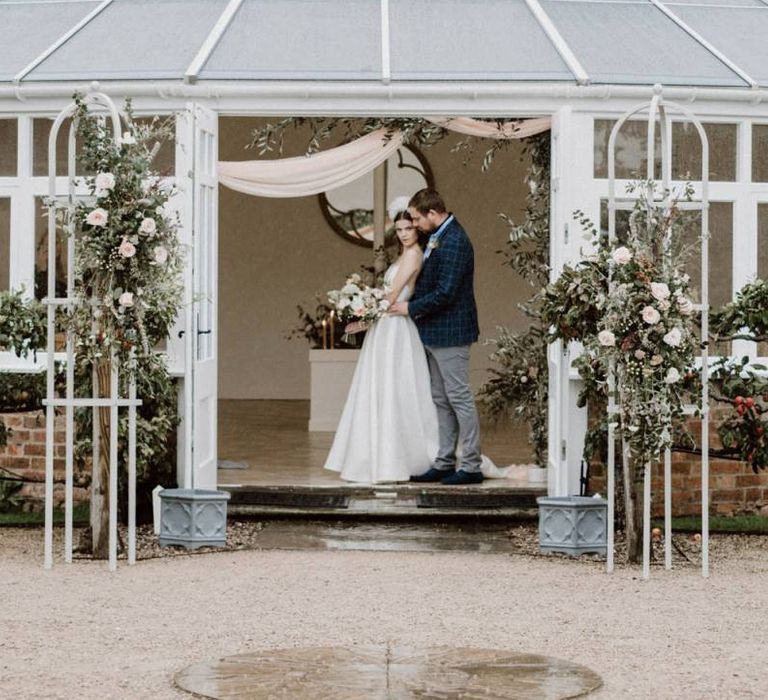 Bride and Groom Standing at the Entrance to Combermere Abbey's Glasshouse