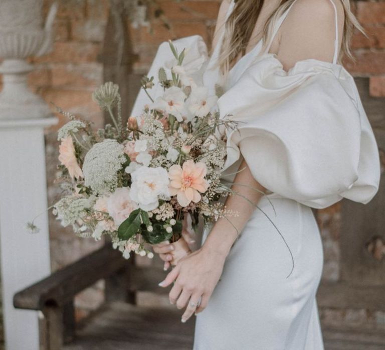 Bride in Puffed Sleeve Wedding Dress Holding a Peach and White Wedding Bouquet