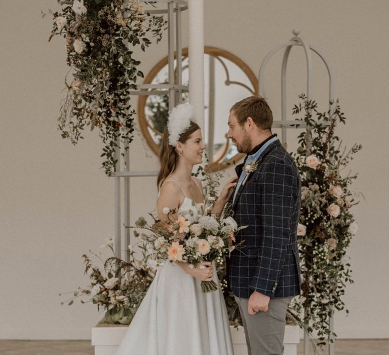 Bride and Groom Standing Next to a Pretty Floral Arrangement