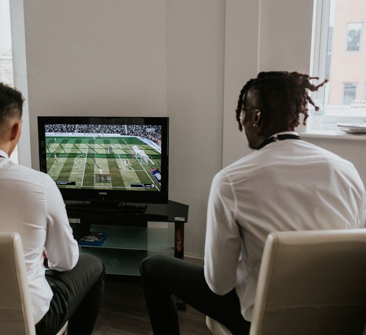 Groom and best man playing computer games on the wedding morning