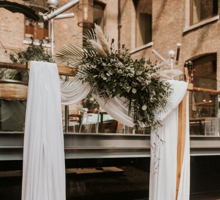 Drapped altar with green foliage and pampas grass at Devonshire Terrace wedding