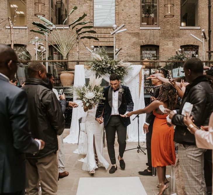 Confetti capture as black bride and groom walk up the aisle