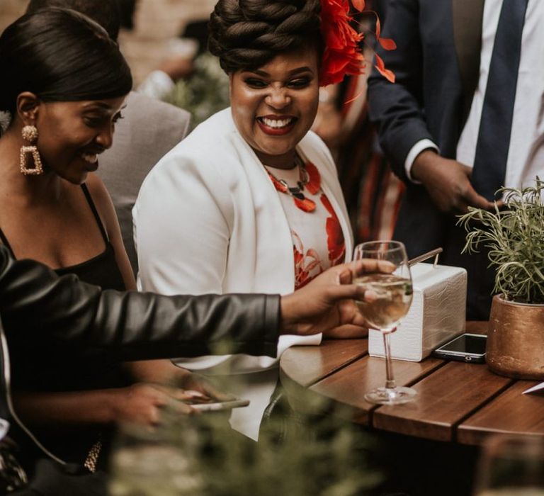 Black wedding guest with braided hair up do and feather hair accessory