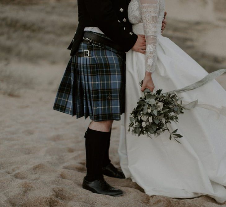 Bride Holds Bouquet And Groom In Kilt for Holywell Bay portraits