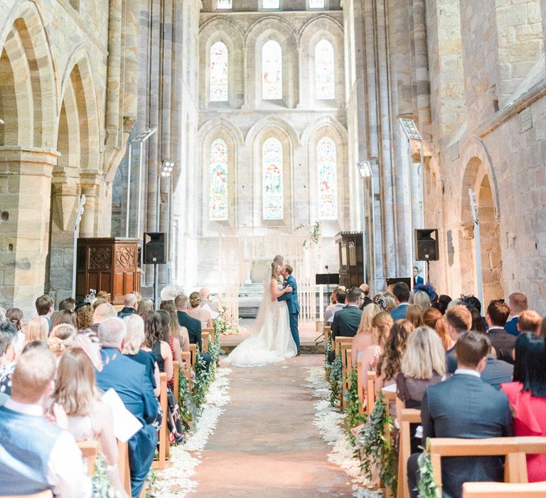 Wedding Ceremony | First Kiss | Bride in Strapless Liz Martinez Ballgown Wedding Dress with Embroidered Flowers | Cathedral Length Veil in Blush Soft Tulle | Groom in Navy Blue Suit with Burgundy Braces, Bow Tie and Brogues | Petal Aisle Decor | Country Tipi Wedding with Macramé Arch and Hanging Flowers | Sarah-Jane Ethan Photography