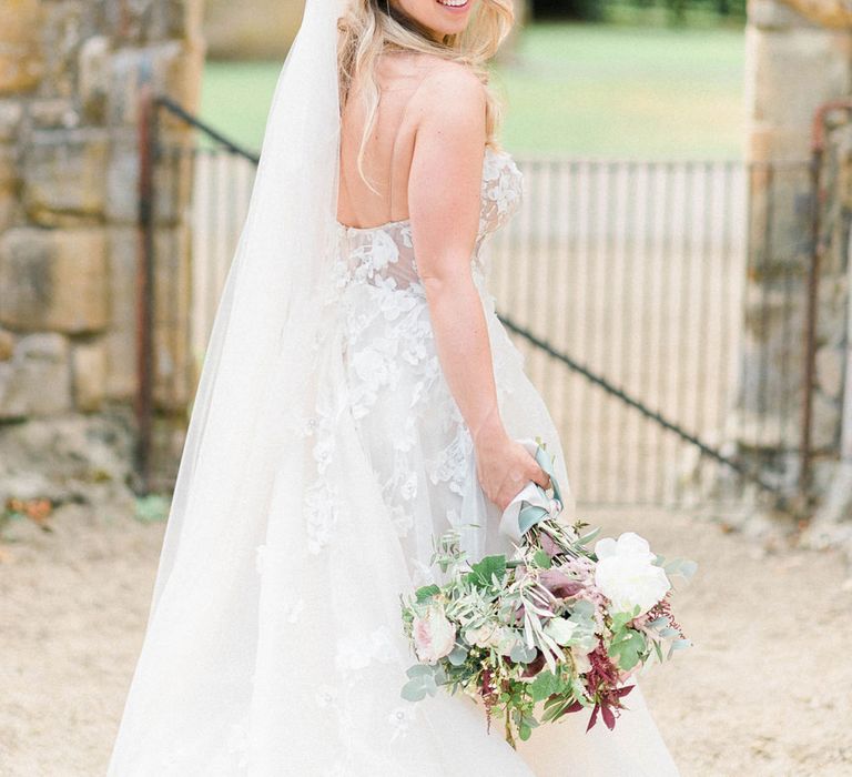 Bride in Strapless Liz Martinez Ballgown Wedding Dress with Embroidered Flowers | Cathedral Length Veil in Blush Soft Tulle | Bridal Bouquet of White Peonies, Blush Astlibe, Trailing Greenery and Burgundy Eucalyptus | Country Tipi Wedding with Macramé Arch and Hanging Flowers | Sarah-Jane Ethan Photography