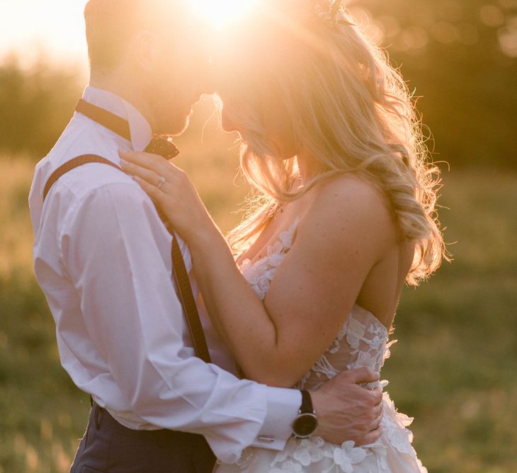 Golden Hour Couples Shot | Bride in Strapless Liz Martinez Ballgown Wedding Dress with Embroidered Flowers | Groom in Navy Blue Suit with Burgundy Braces, Bow Tie and Brogues | Country Tipi Wedding with Macramé Arch and Hanging Flowers | Sarah-Jane Ethan Photography