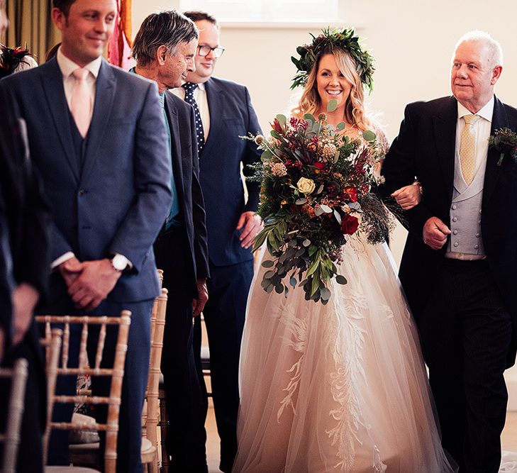 Bride in Riki Dalal wedding dress with foliage crown and large bouquet walks down the aisle