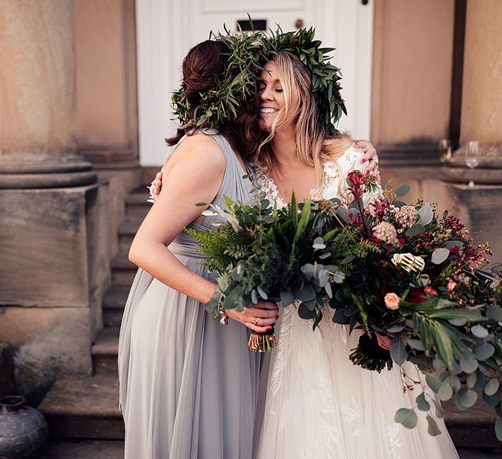 Bride with large bouquet hugs bridesmaid