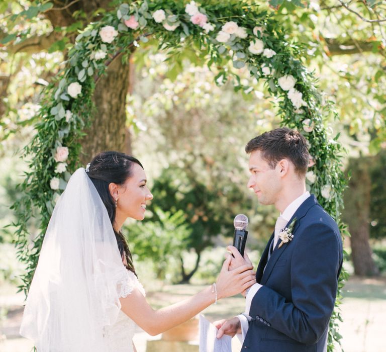 Bride in Lace David Tutera Wedding Dress and Groom in Navy Three Piece Suit  Exchanging Vows