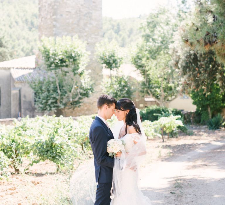 Bride in Lace David Tutera Wedding Dress and Groom in Navy Three Piece Suit Embracing