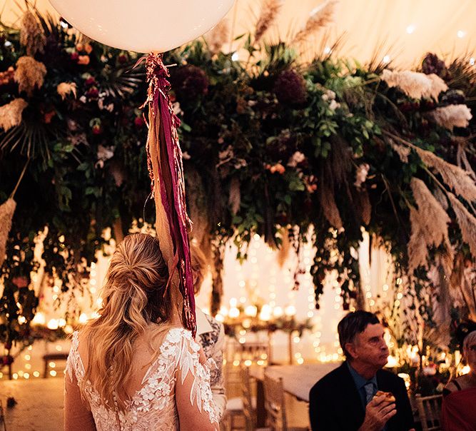 Bride in Riki Dalal wedding dress with tassel balloon and flower installation