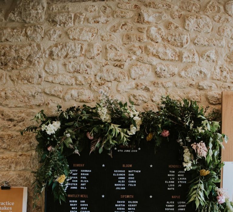 Peg board seating chart with foliage and flower decor