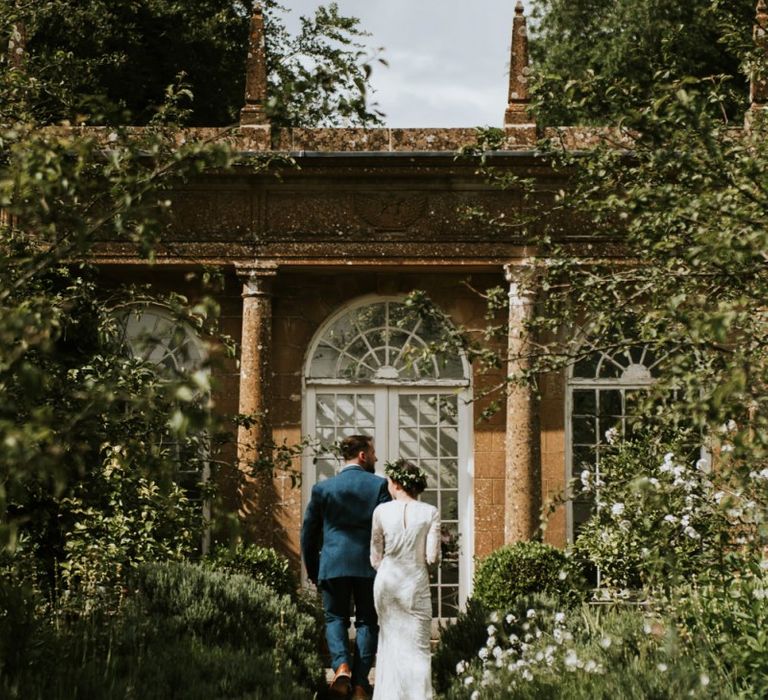 Bride in Savannah Miller wedding dress and groom take stroll through venue grounds in Dorset