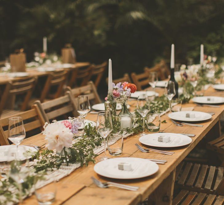 Glass bottle candle holders with foliage and macrame table runner