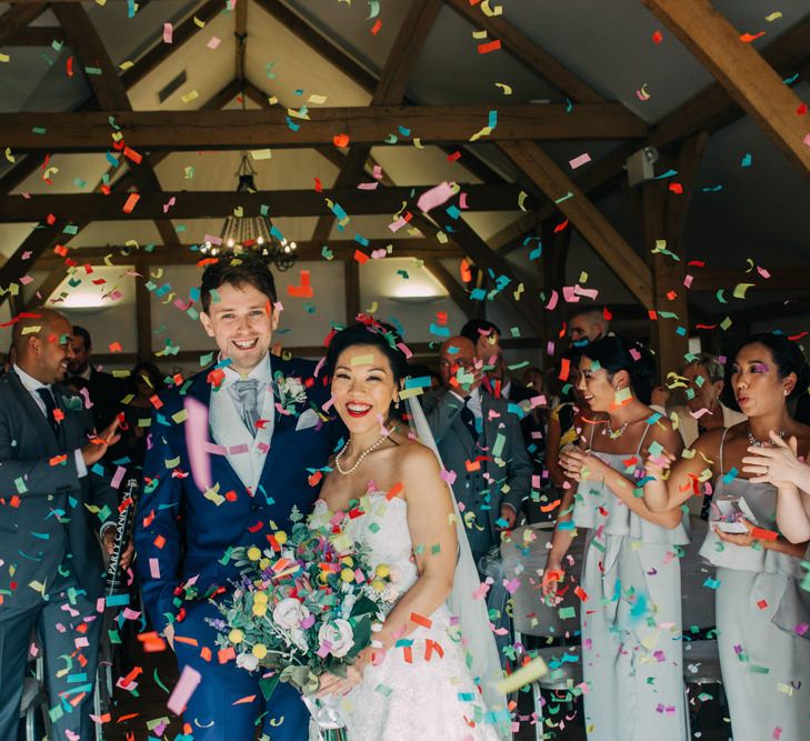 Colourful Confetti Bomb with Bride in Princess Wedding Dress and Groom in Navy Suit