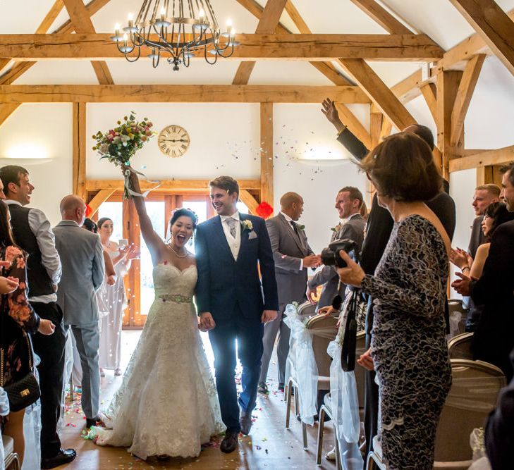 Bride in Princess Wedding Dress and Groom in Navy Suit Walking Up the Aisle After Getting Married