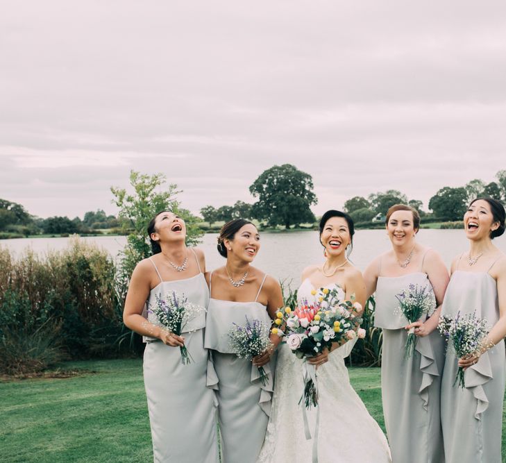 Laughing Bridal Party Portrait with Bride in Princess Wedding Dress and Bridesmaids in Grey Dresses