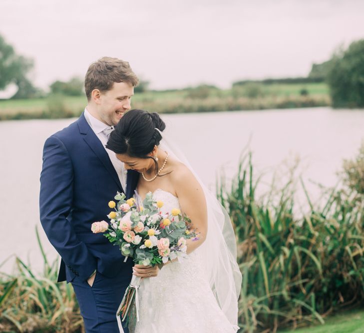 Bride and Groom Portrait by the Lake with Bride in Bandeau Wedding Dress and Groom in Navy Suit