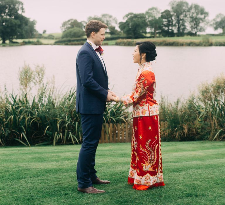 Bride in red Chinese wedding dress and groom in Black tuxedo by the lake