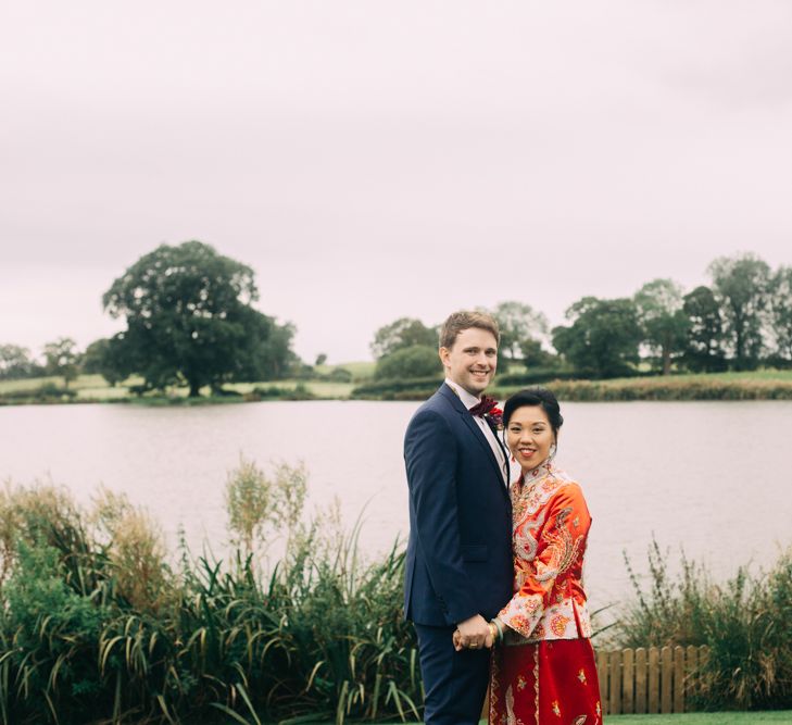 Bride in red Chinese wedding dress and groom in Black tuxedo Embracing