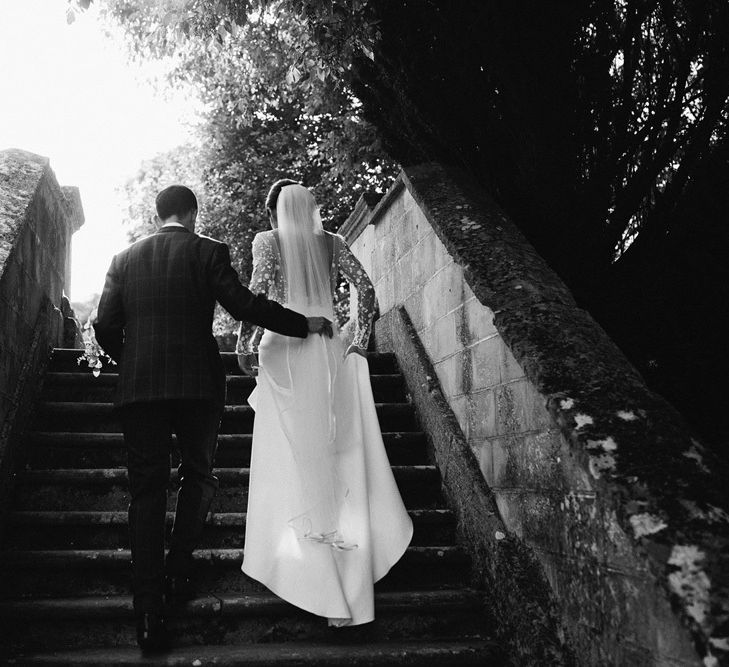 Groom Holding his Brides Train as She Walks Up Steps