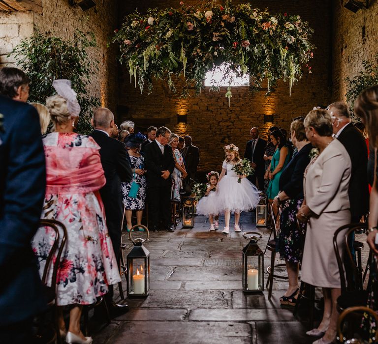 Flower Girls in Tulle Tutu Walking Down the Aisle with a Greenery Chandelier