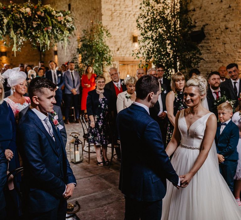 Bride in Stella York Wedding Dress with Tulle Skirt and Groom in Navy Suit Exchanging Vows at Cripps Barn Altar